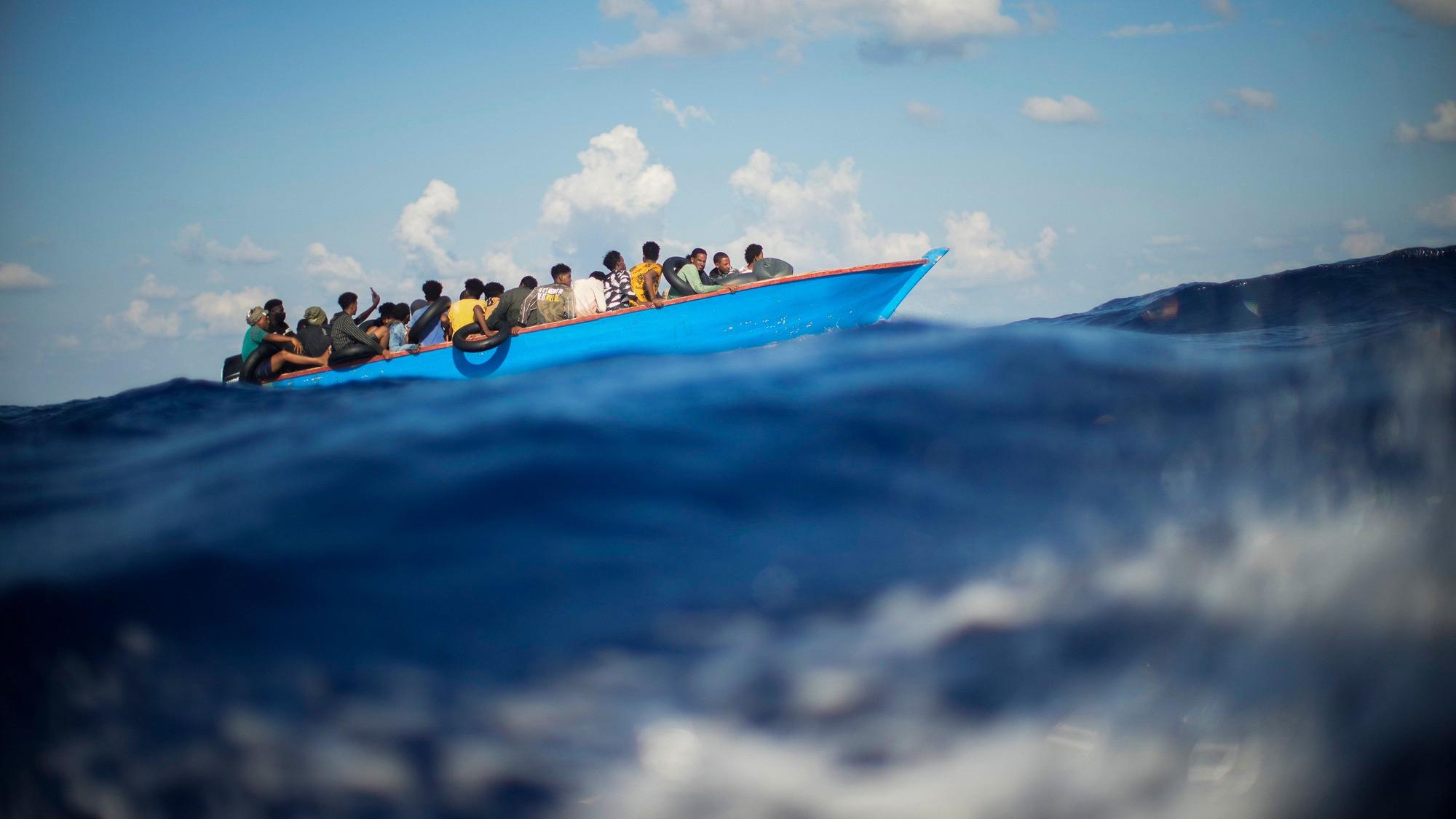 ARCHIV - 11.08.2022, Italien, ---: Migranten sitzen in einem Holzboot im Mittelmeer nahe der Insel Lampedusa. (zu dpa «Erneut Hunderte Bootsmigranten auf Lampedusa gelandet») Foto: Francisco Seco/AP/dpa +++ dpa-Bildfunk +++