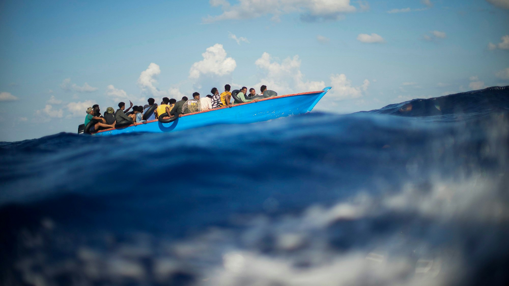 Migrantinnen und Migranten sitzen auf einem Boot im Mittelmeer. (Symbolbild)