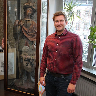 Erwin Nelles (links) und Robin Poensgen stehen an der Vitrine im Blankenheimer Rathaus, in der die Figur des heiligen Nepomuk mit dem Wappen aufbewahrt wird.