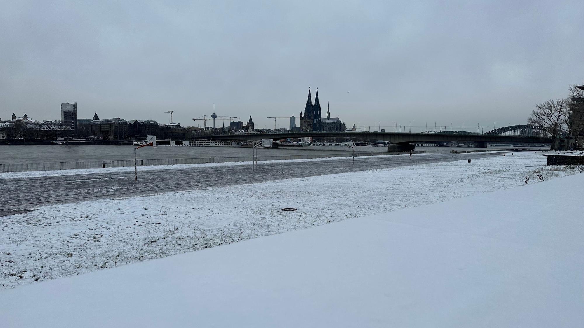 Am Montag, 4. Dezember, liegt noch eine leichte Schneedecke über einigen Teilen Kölns. Am Rhein sind Grünflächen mit Schnee bedeckt.