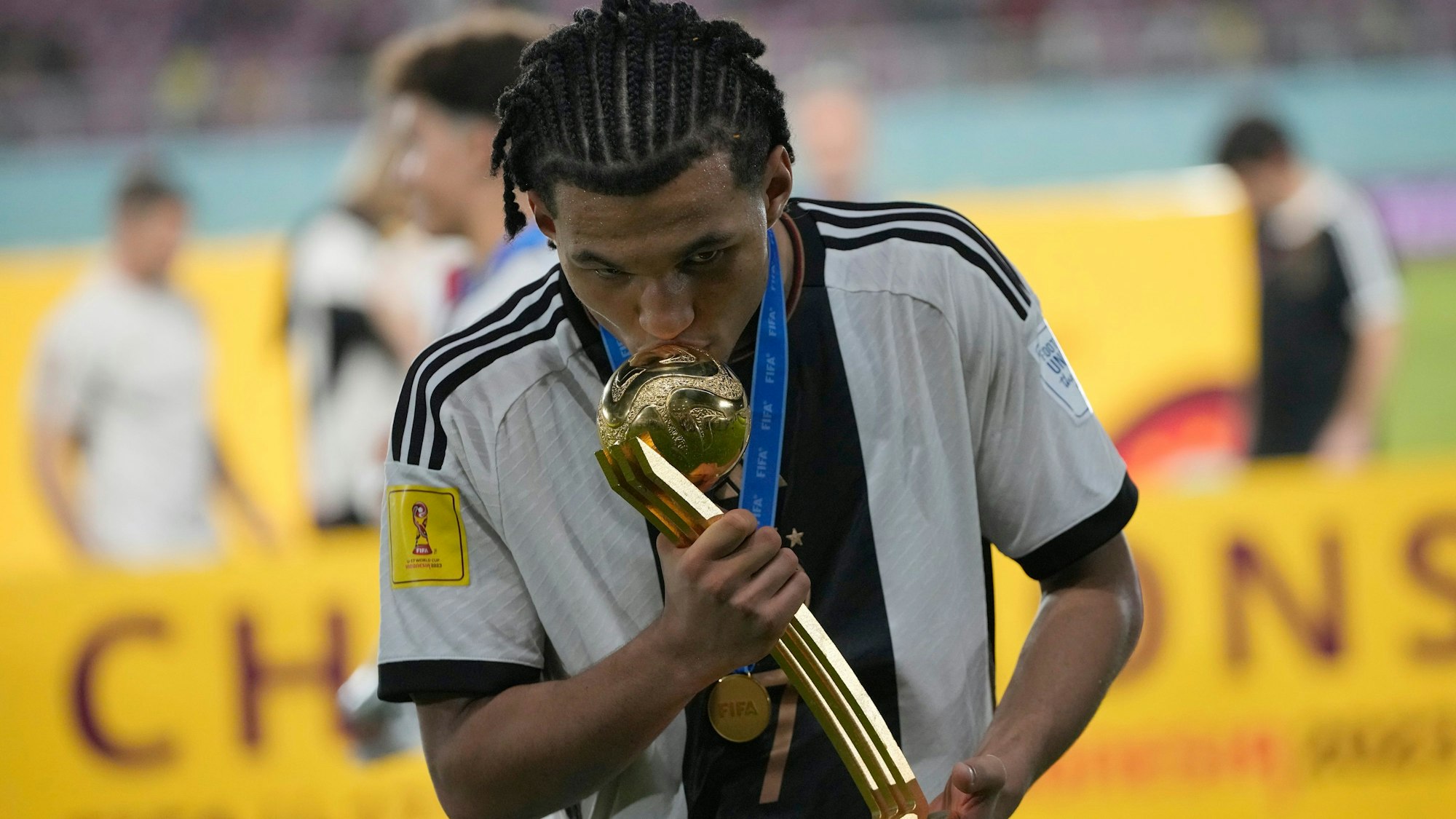 02.12.2023, Indonesien, Surakarta: Fußball, U17-Junioren: WM, Deutschland - Frankreich, Finale im Manahan Stadion. Der deutsche Nationalspieler Paris Brunner küsst die Trophäe des Goldenen Balls nach dem Sieg seiner Mannschaft. Die deutschen U17-Fußballer siegten nach dem 4:3 im Elfmeterschießen. Es ist der erste Titel für den Deutschen Fußball-Bund in dieser Altersklasse. Foto: Achmad Ibrahim/AP +++ dpa-Bildfunk +++