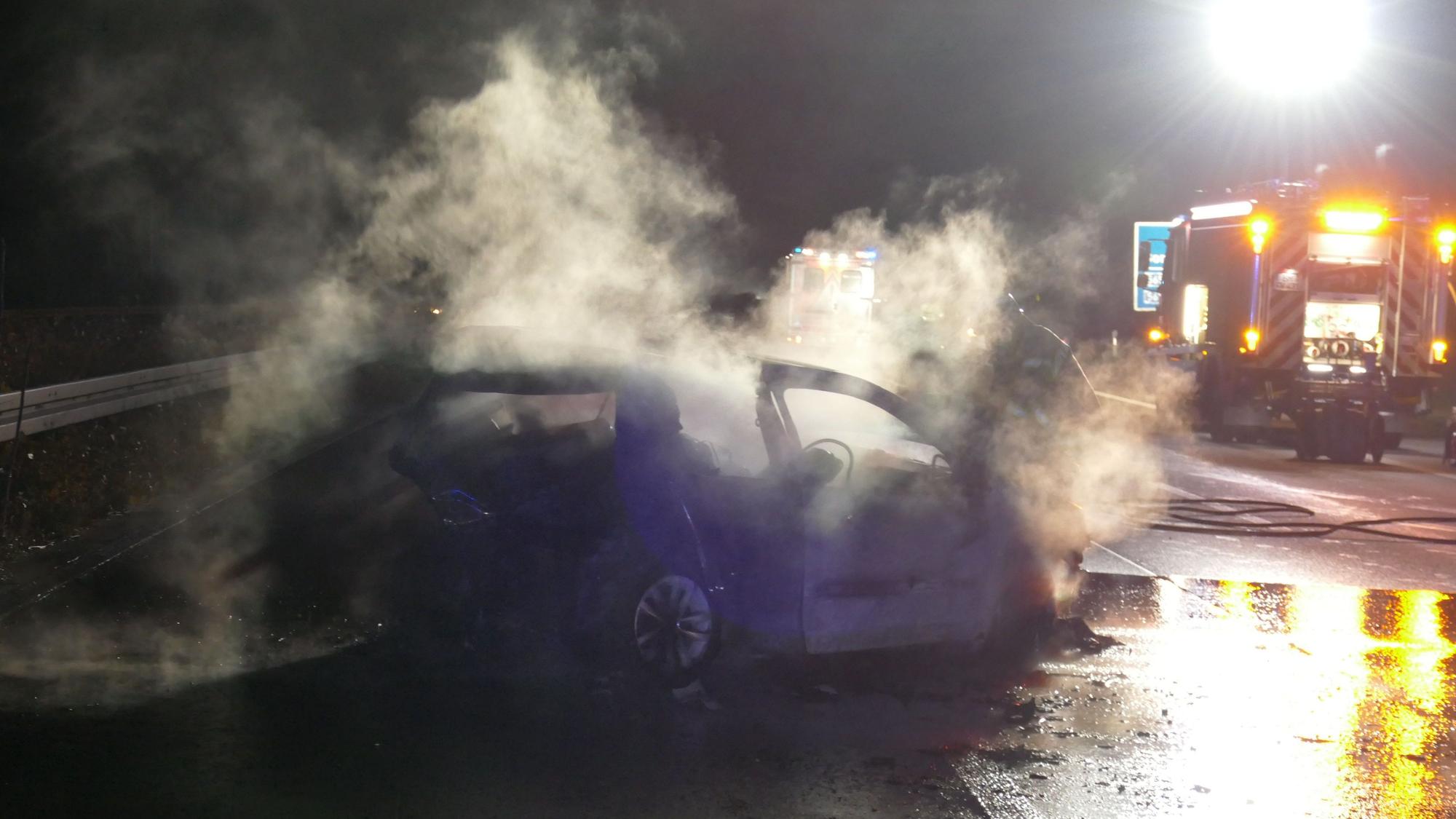 Das Foto zeigt den ausgebrannten Wagen und ein Einsatzfahrzeug der Feuerwehr auf der Autobahn.