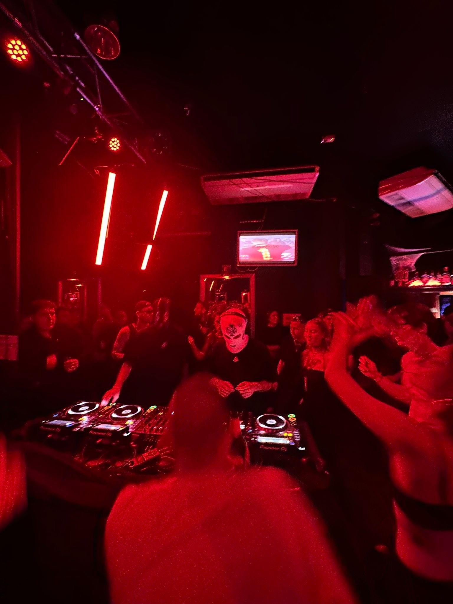 Ein DJ legt auf, Menschen tanzen drumherum.