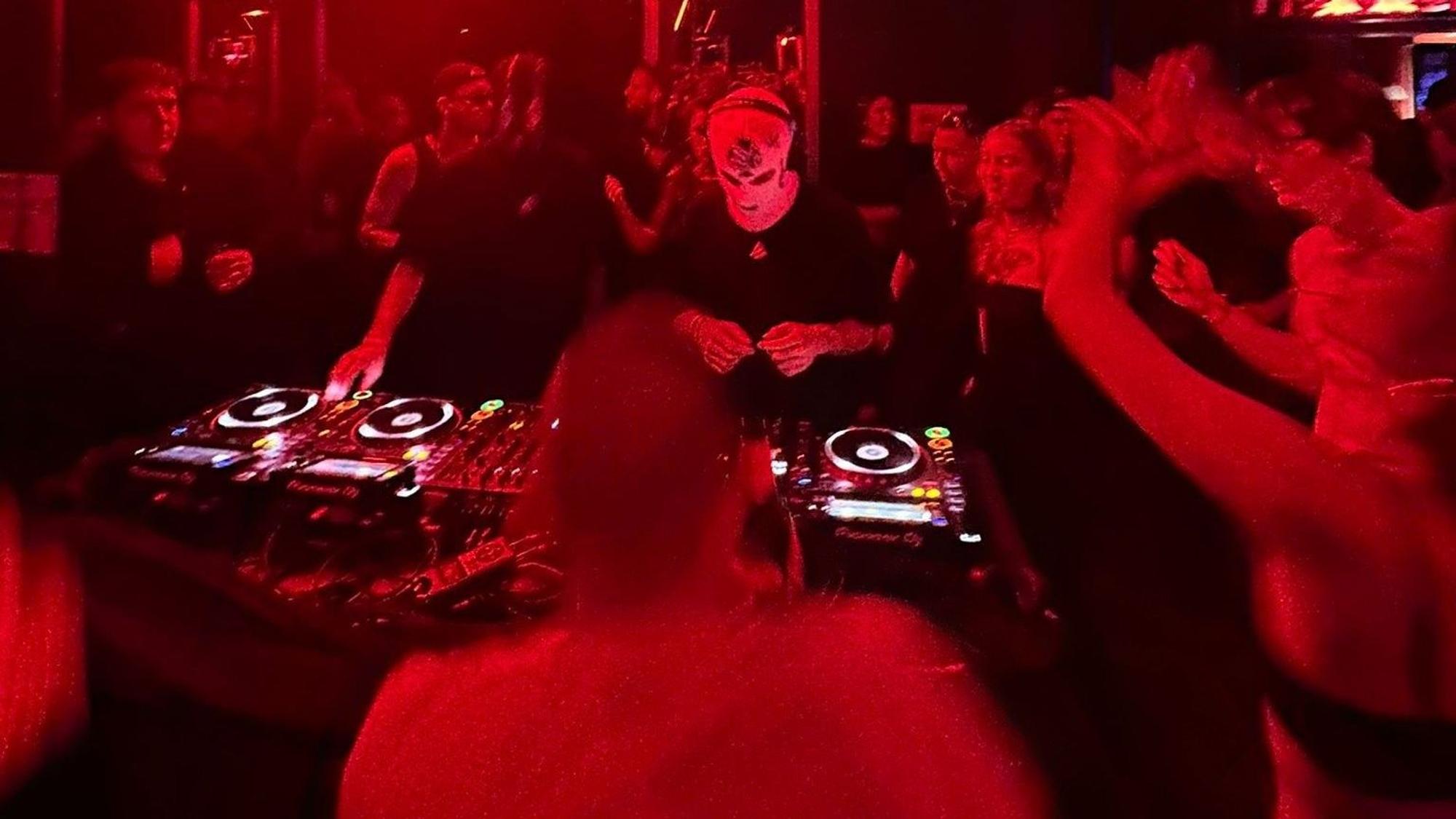 Ein DJ legt auf, Menschen tanzen drumherum.