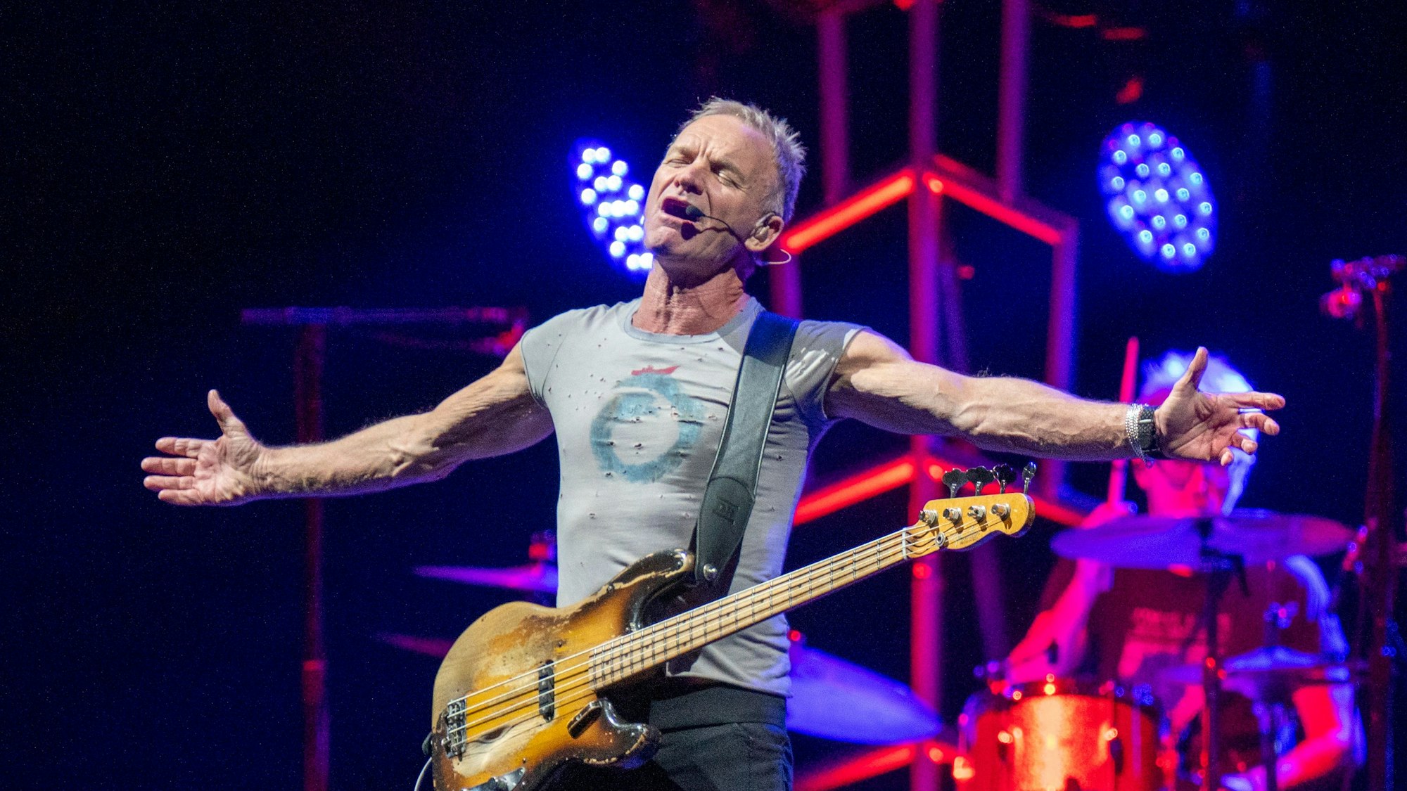 Sting breitet die Arme aus, er hat die Augen gescbhlossen und singt.