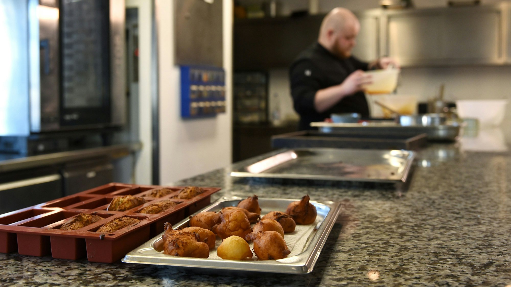 Fotoaufnahme aus der Küche, im Hintergrund ist der Patissier des Jahres.