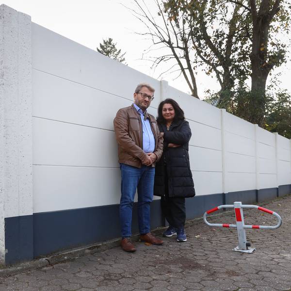 Zwei Menschen stehen vor einer Häuserwand.