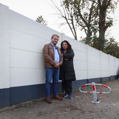 Zwei Menschen stehen vor einer Häuserwand.