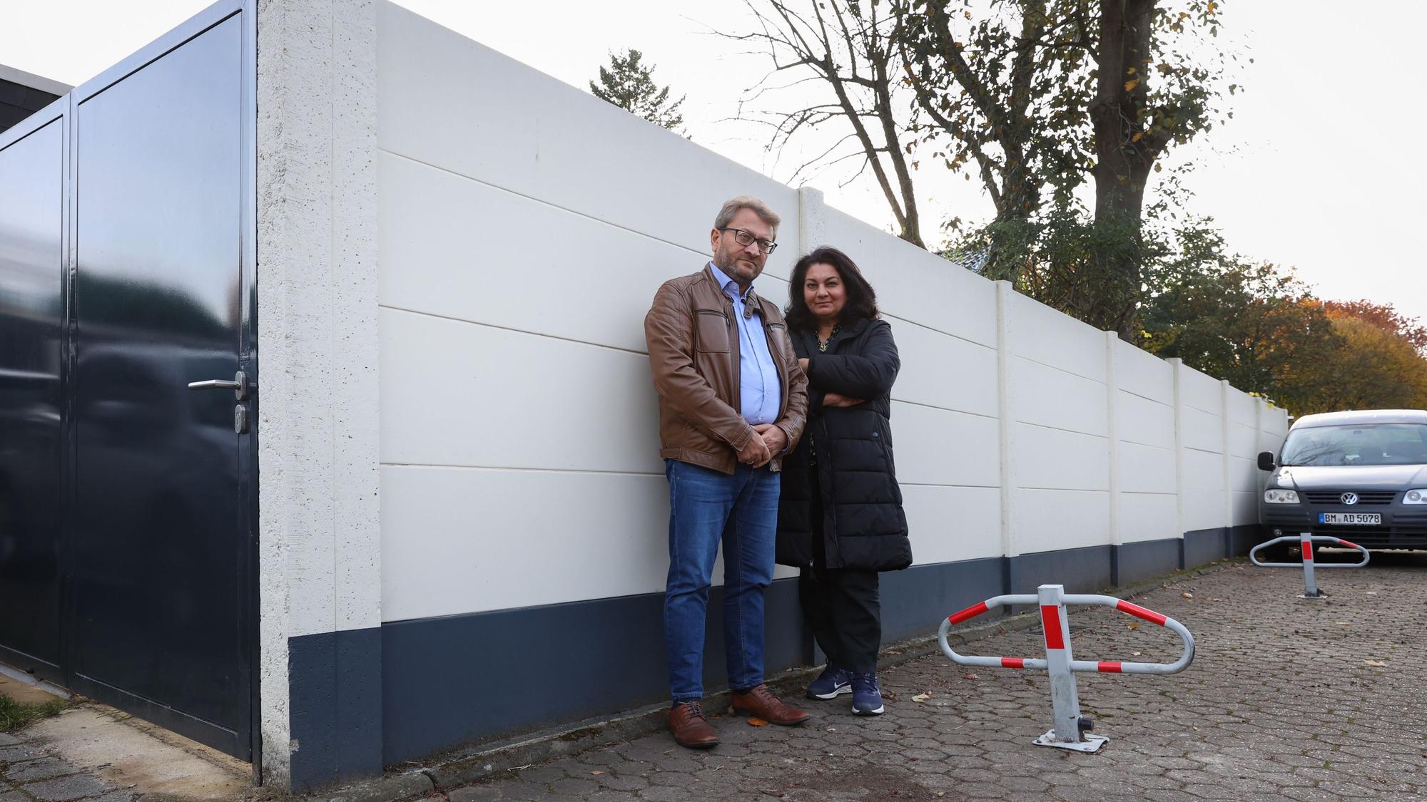 Zwei Menschen stehen vor einer Häuserwand.