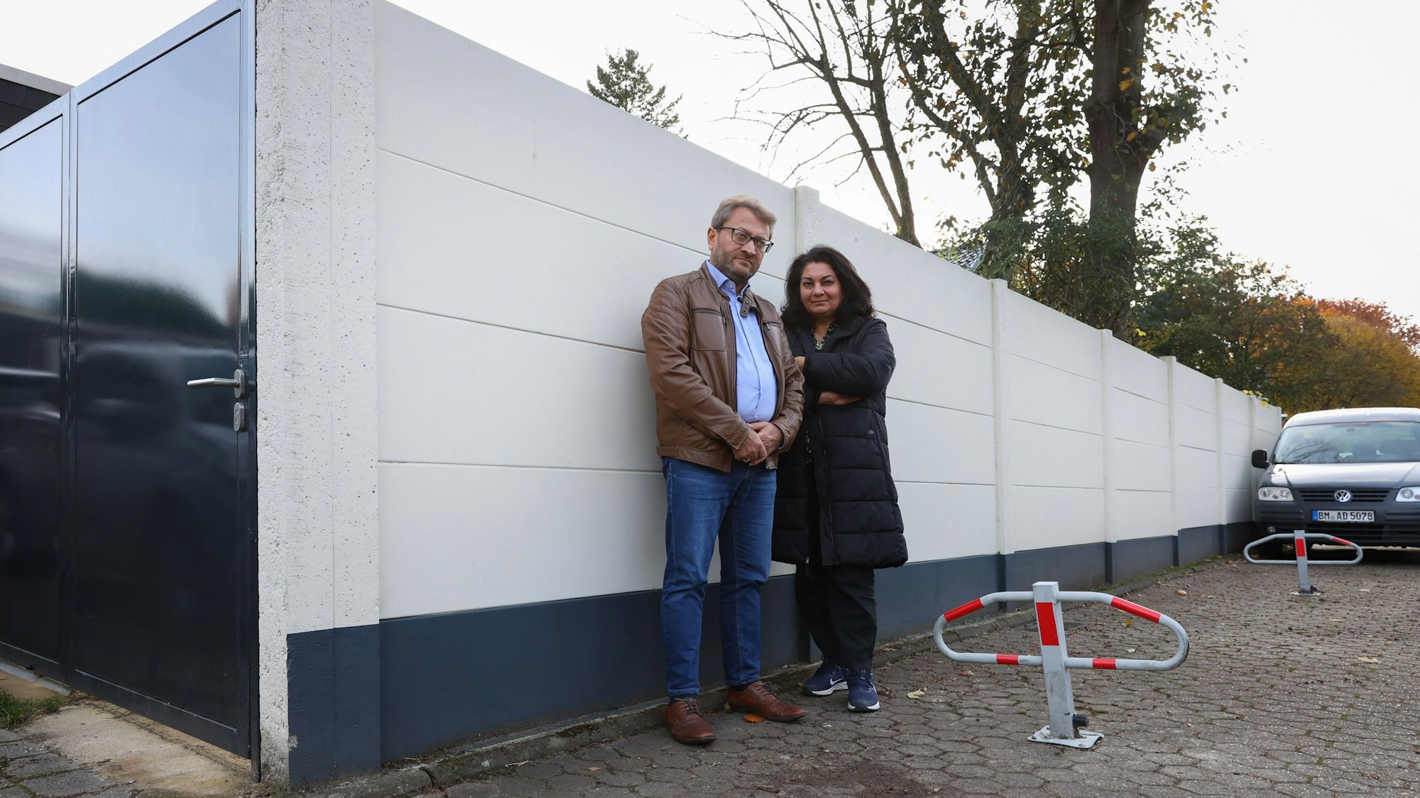 Zwei Menschen stehen vor einer Häuserwand.