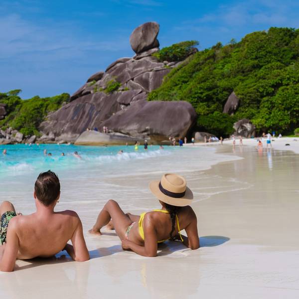 Ein Pärchen sitzt am einem Strand in Thailand.