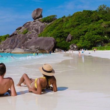 Ein Pärchen sitzt am einem Strand in Thailand.