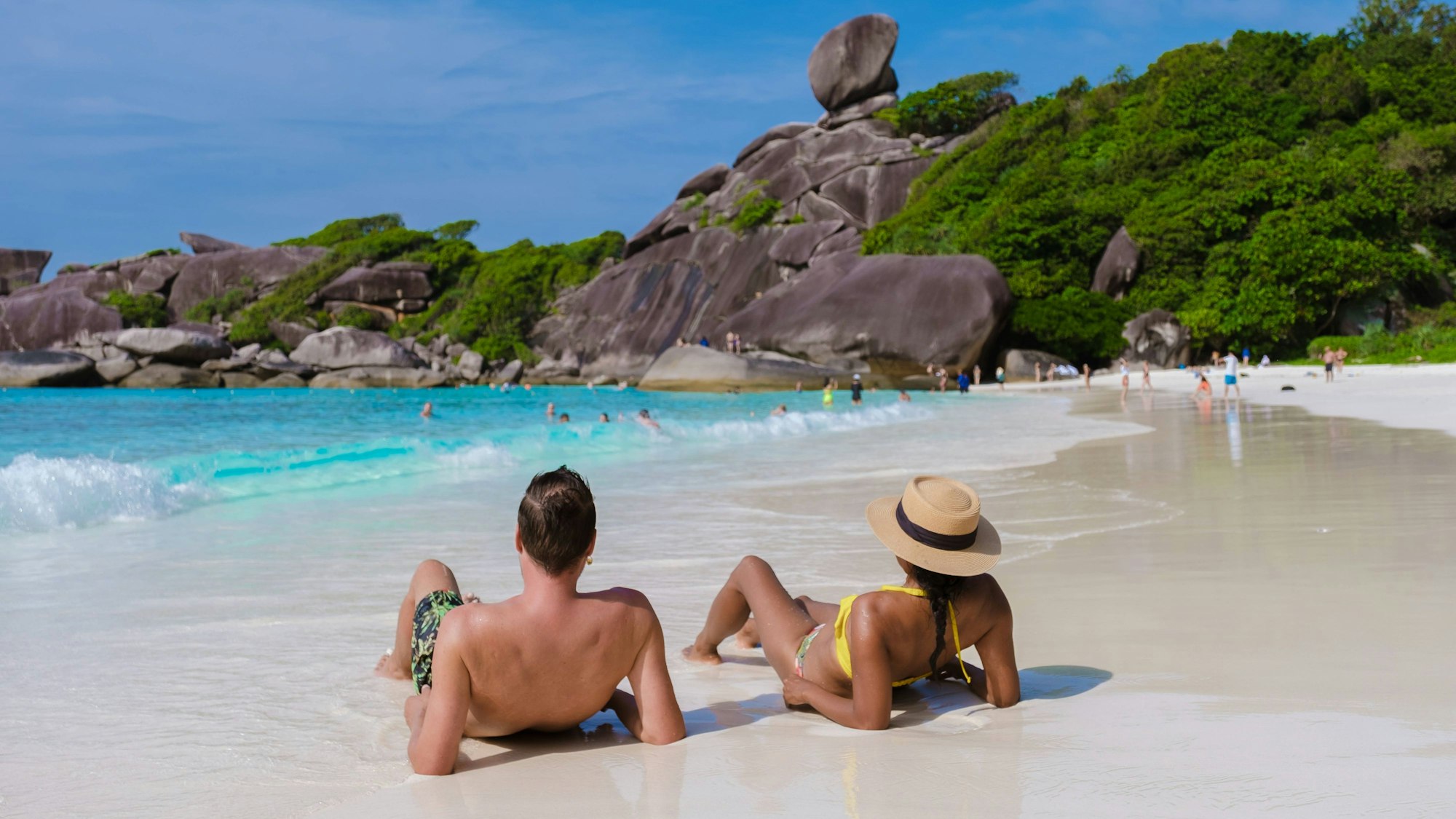 Ein Pärchen sitzt am einem Strand in Thailand.