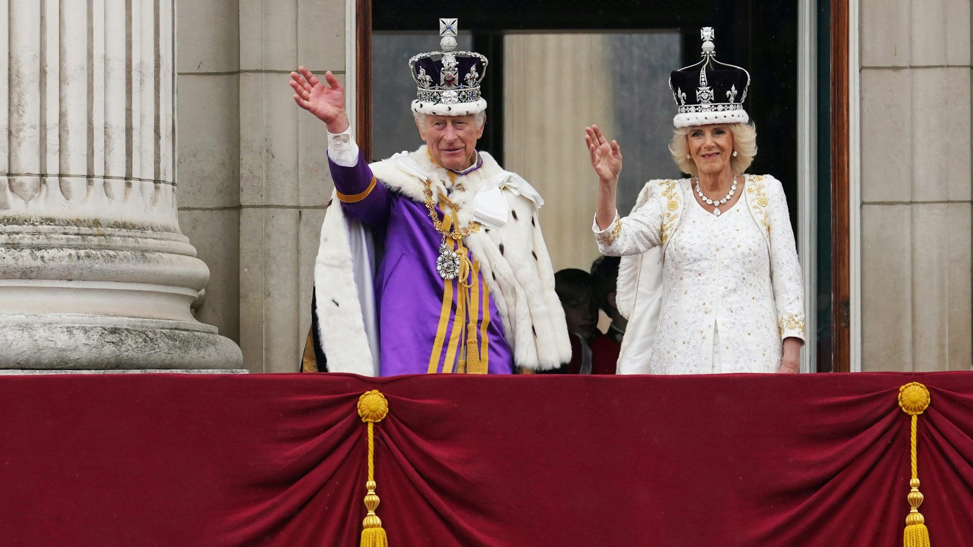König Charles III. und Königin Camilla winken nach der Krönungszeremonie vom Balkon des Buckingham Palastes aus der Menge zu. (Archivbild)