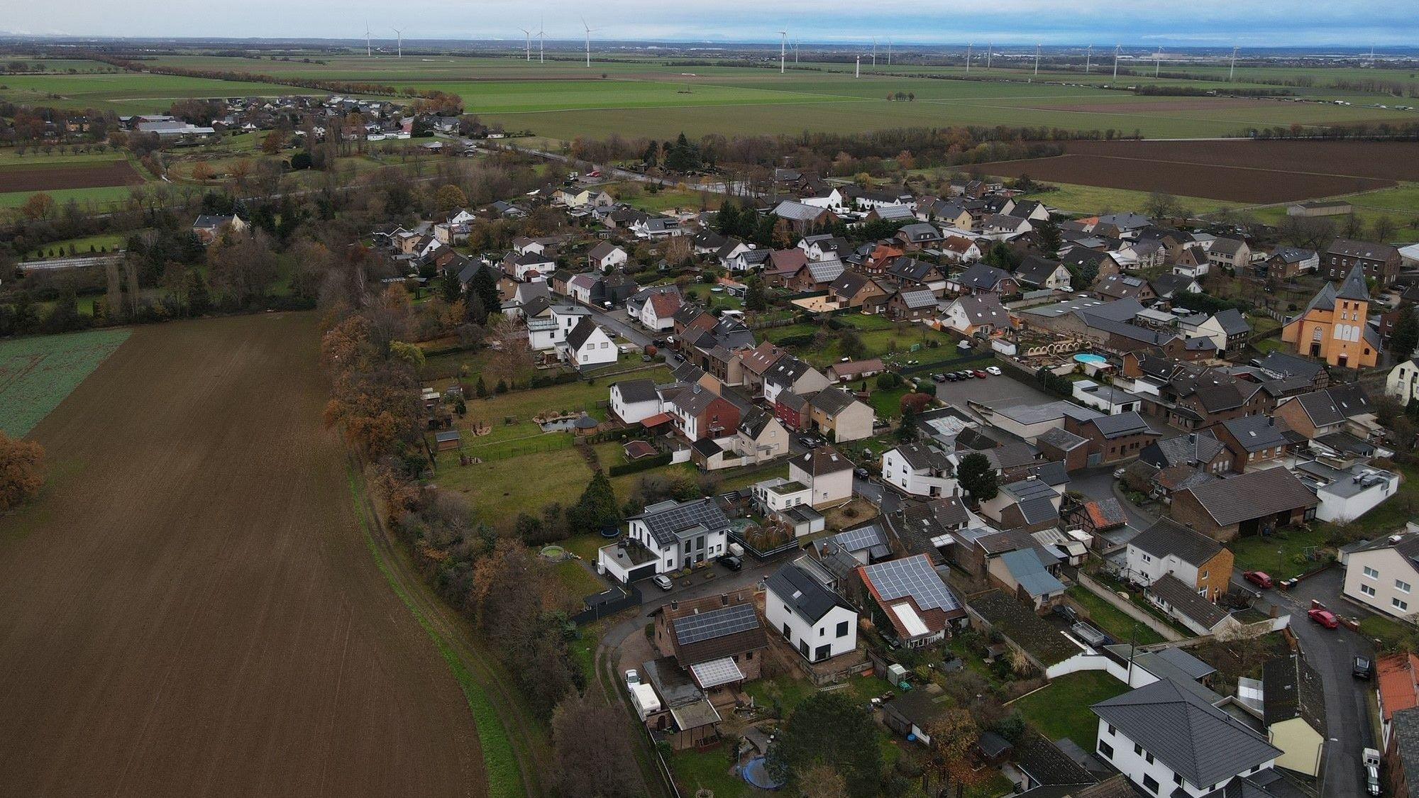 Das Bild zeigt den Ort Frauenberg aus der Luft fotografiert. Am Horizont sind Windräder zu erahnen.