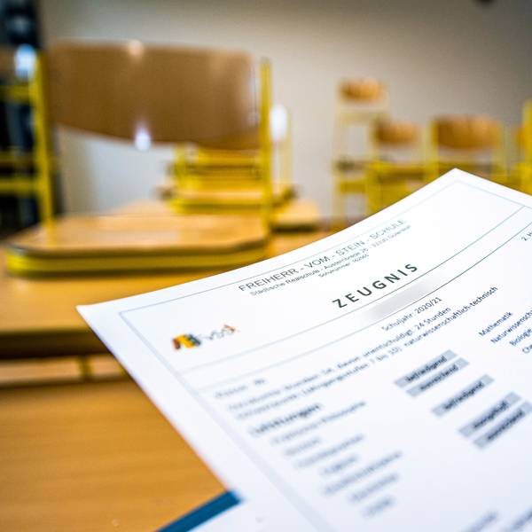 ARCHIV - 02.07.2021, Nordrhein-Westfalen, Gütersloh: Eine Klassenlehrerin hält das Zeugnis eines Schülers einer Schule in Gütersloh hoch. Bei Sorgen und Nöten rund ums Zeugnis schalten die fünf NRW-Bezirksregierungen auch in diesem Jahr wieder das Zeugnistelefon. Es dient dazu, eine «telefonische Rechtsberatung bei Fragen zu Noten und zur Schullaufbahn» zu liefern, wie die Bezirksregierungen mitteilen. (zu dpa: «Zeugnistelefone der Bezirksregierungen wieder erreichbar») Foto: David Inderlied/dpa +++ dpa-Bildfunk +++