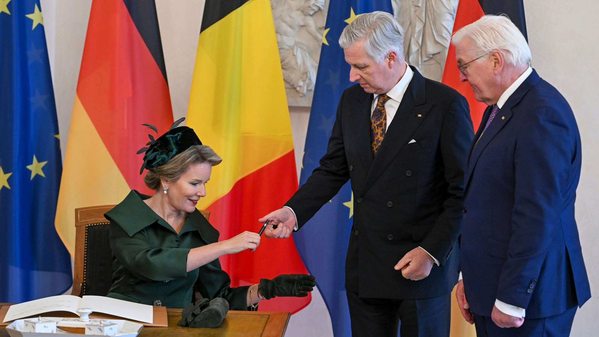 Das belgische Königspaar König Philippe (m.) und Königin Mathilde tragen sich in das Gästebuch im Schloss Bellevue ein, während Bundespräsident Frank-Walter Steinmeier neben ihnen steht.
