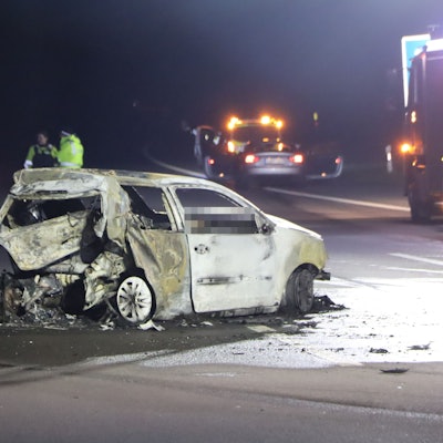 Einsatzkräfte stehen in der Nacht auf der Autobahn in der Nähe eines ausgebrannten VW-Polos. Die Autobahn, auf der der Wagen steht, ist komplett gesperrt.