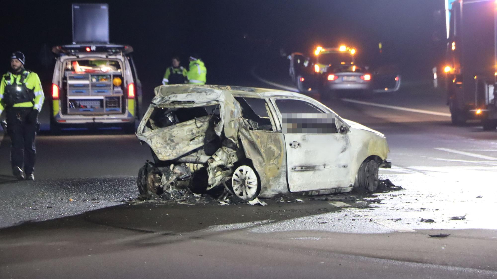 Einsatzkräfte stehen in der Nacht auf der Autobahn in der Nähe eines ausgebrannten VW-Polos. Die Autobahn, auf der der Wagen steht, ist komplett gesperrt.