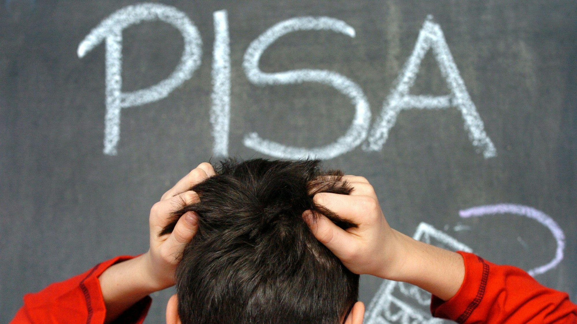 Ein Schüler rauft sich in vor dem mit Kreide an eine Schultafel geschriebenen Wort PISA die Haare. Das Ergebnis des Pisa-Test fiel schlecht aus