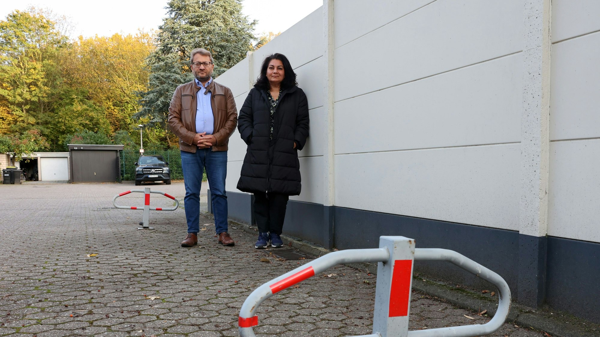 Zwei Menschen stehen vor einer Häuserwand.