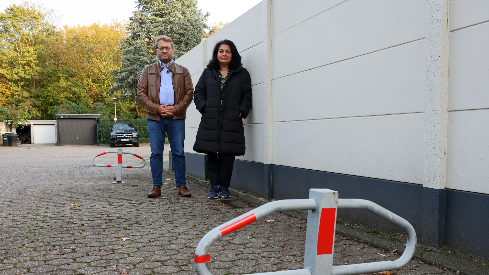 Latif Bekiri und Perwin Sakar stehen vor der Mauer vor ihrem Grundstück. Im Vordergrund ein Poller.