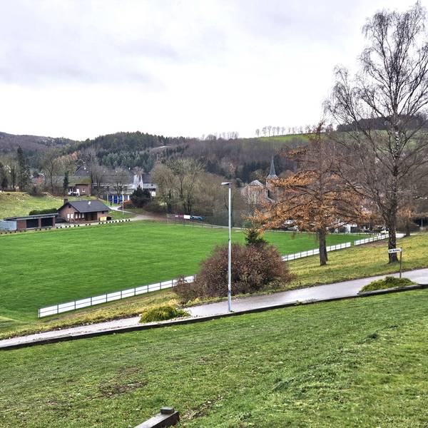 Zu sehen ist ein Blick vom Hang auf den Sötenicher Sportplatz.