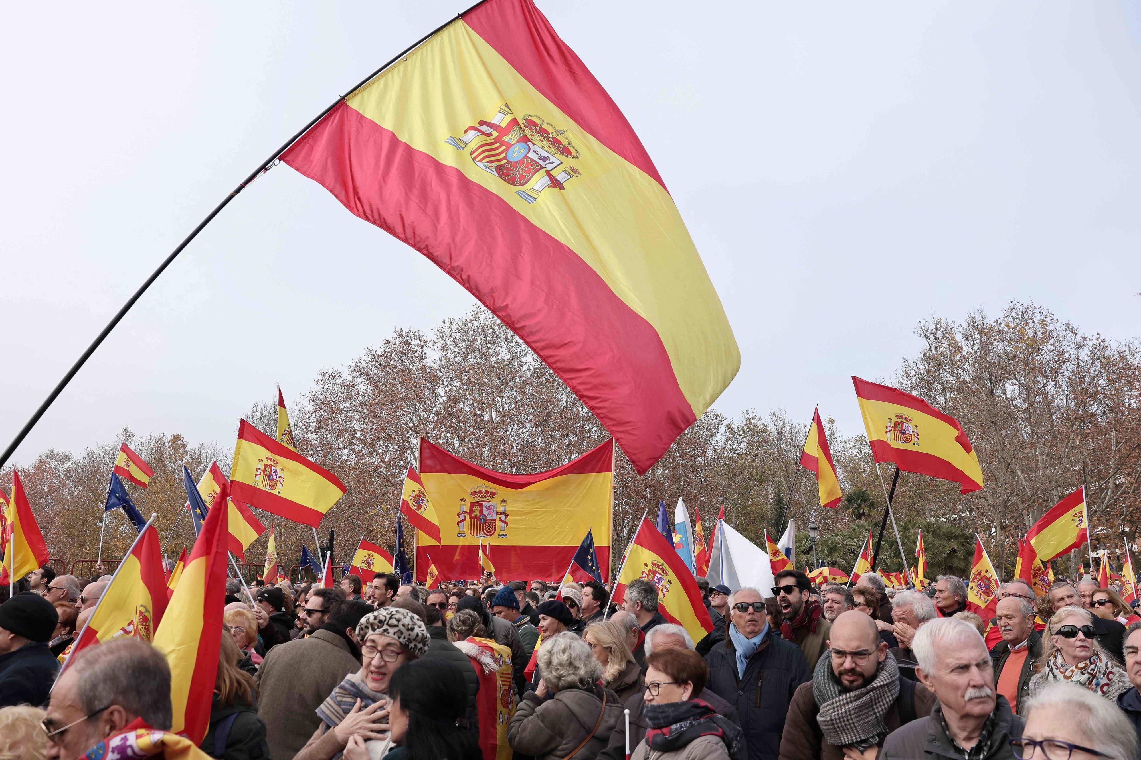Protestors wave Spanish national flag as they take part in a demonstration called by opposition party Partido Popular (PP) against the government's amnesty bill for people involved in Catalonia's failed 2017 independence bid, in Madrid on December 3, 2023. (Photo by Thomas COEX / AFP)