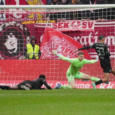 Jonas Urbig wirft sich in den Schuss eines Fußballspielers.