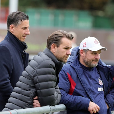 Prüfende Blicke beim FC Training: Christian Keller, Thomas Kessler und Steffen Baumgart stehen am Geißbockheim am Spielfeldrand.