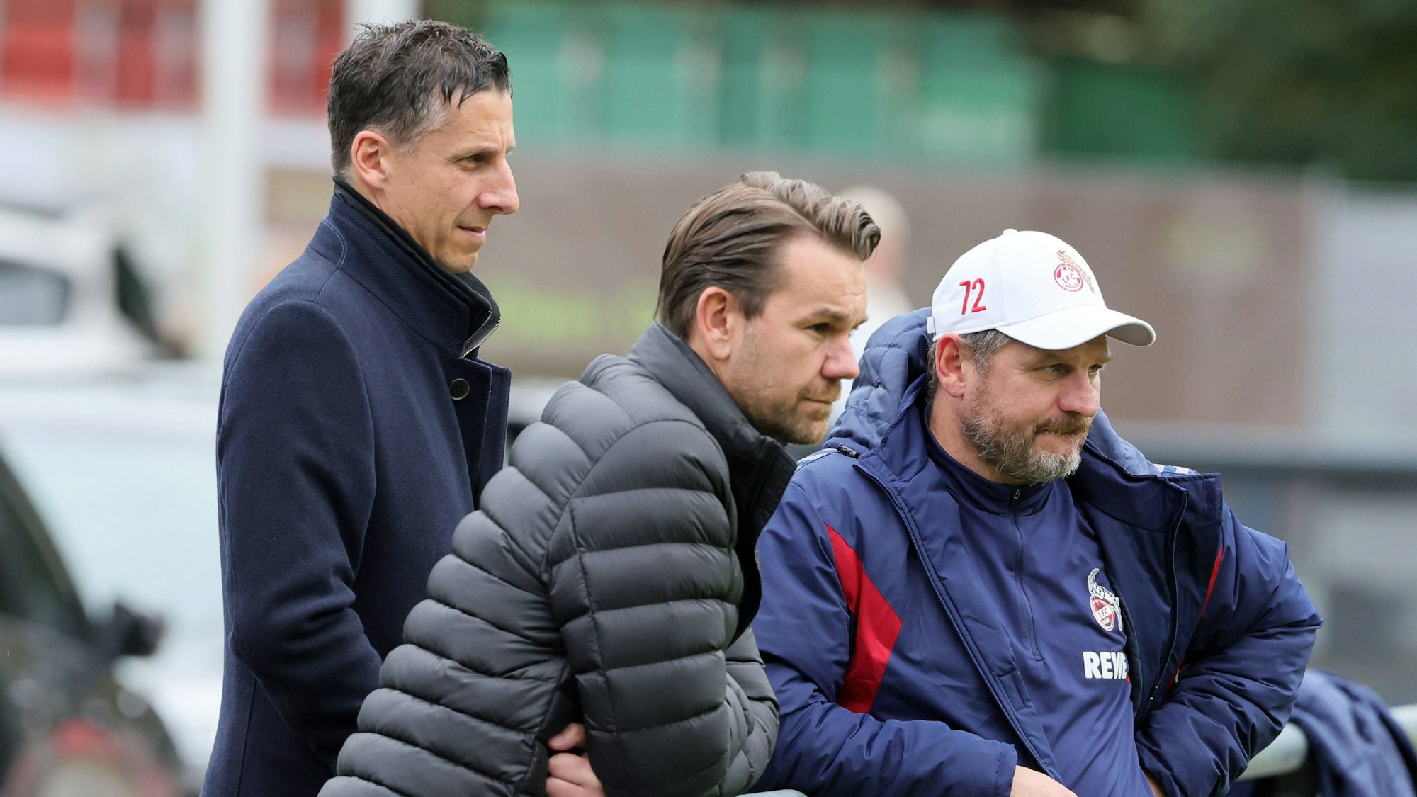 Prüfende Blicke beim FC Training: Christian Keller, Thomas Kessler und Steffen Baumgart stehen am Geißbockheim am Spielfeldrand.