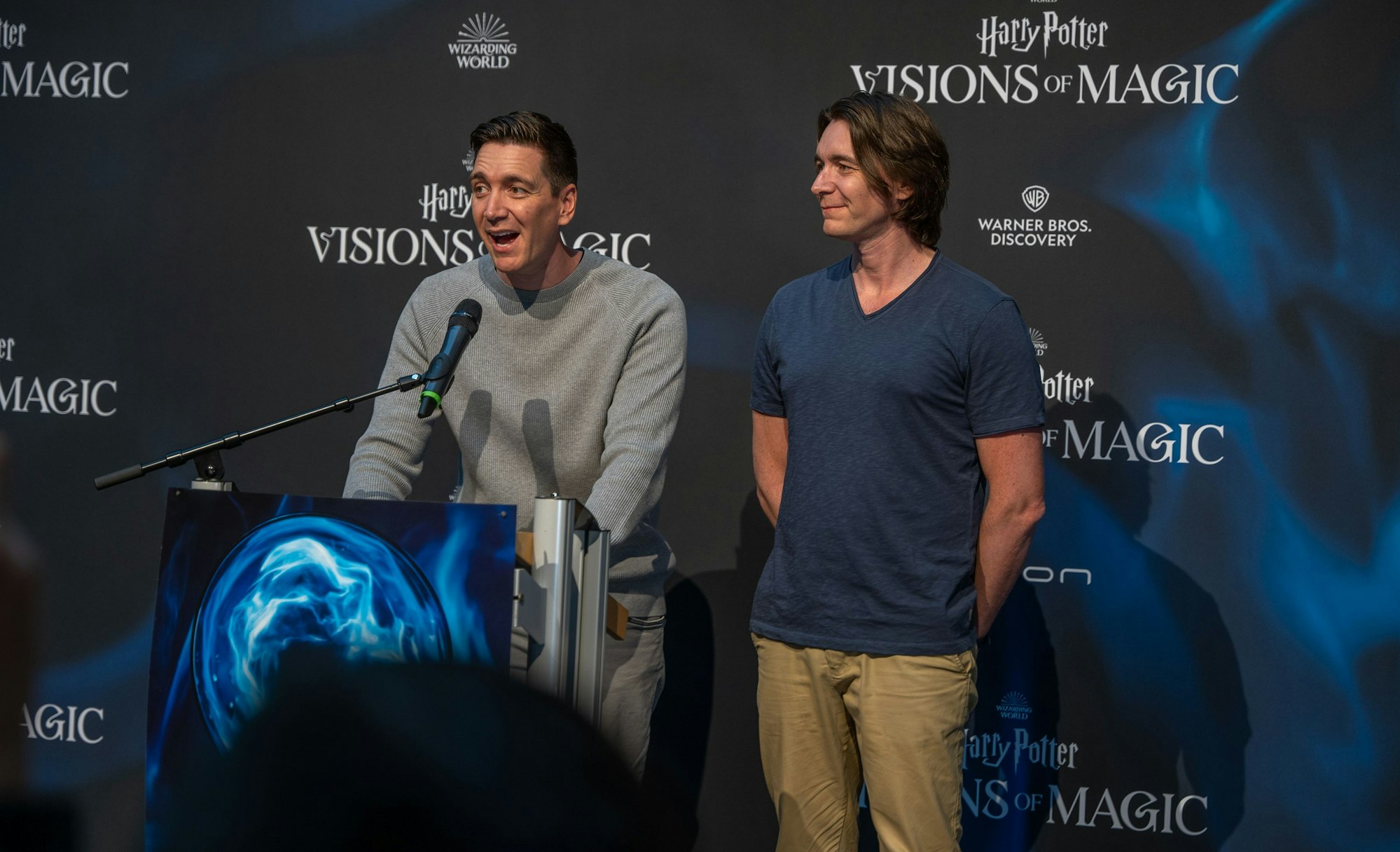 Oliver und James Phelps (v.l.) stehen vor einem Sprecherpult mit Mikrofon.