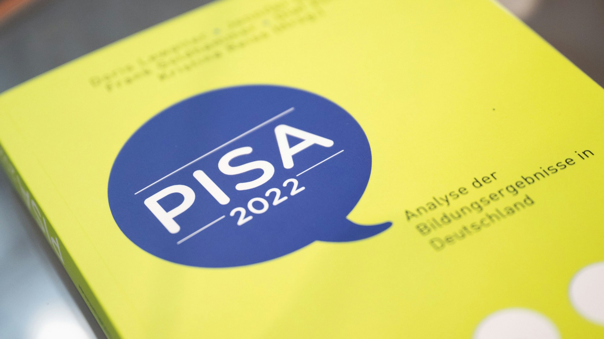 Das Foto zeigt die Pisa-Studie 2022, in gelbem Einband und mit einer blauen Sprechblase, die in weißer Schrift den Titel „PISA 2022“ trägt. Der Untertitel in schwarzer Schrift auf gelbem Grund lautet: „Analyse der Bildungsergebnisse in Deutschland“