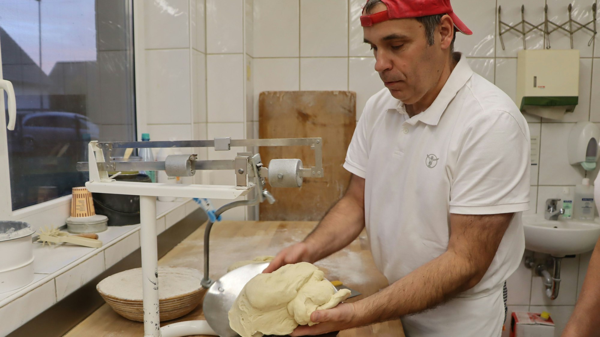 Auf dem Foto ist Bäckermeister Peter Weber zu sehen. Er wiegt den speziellen Teig ab.