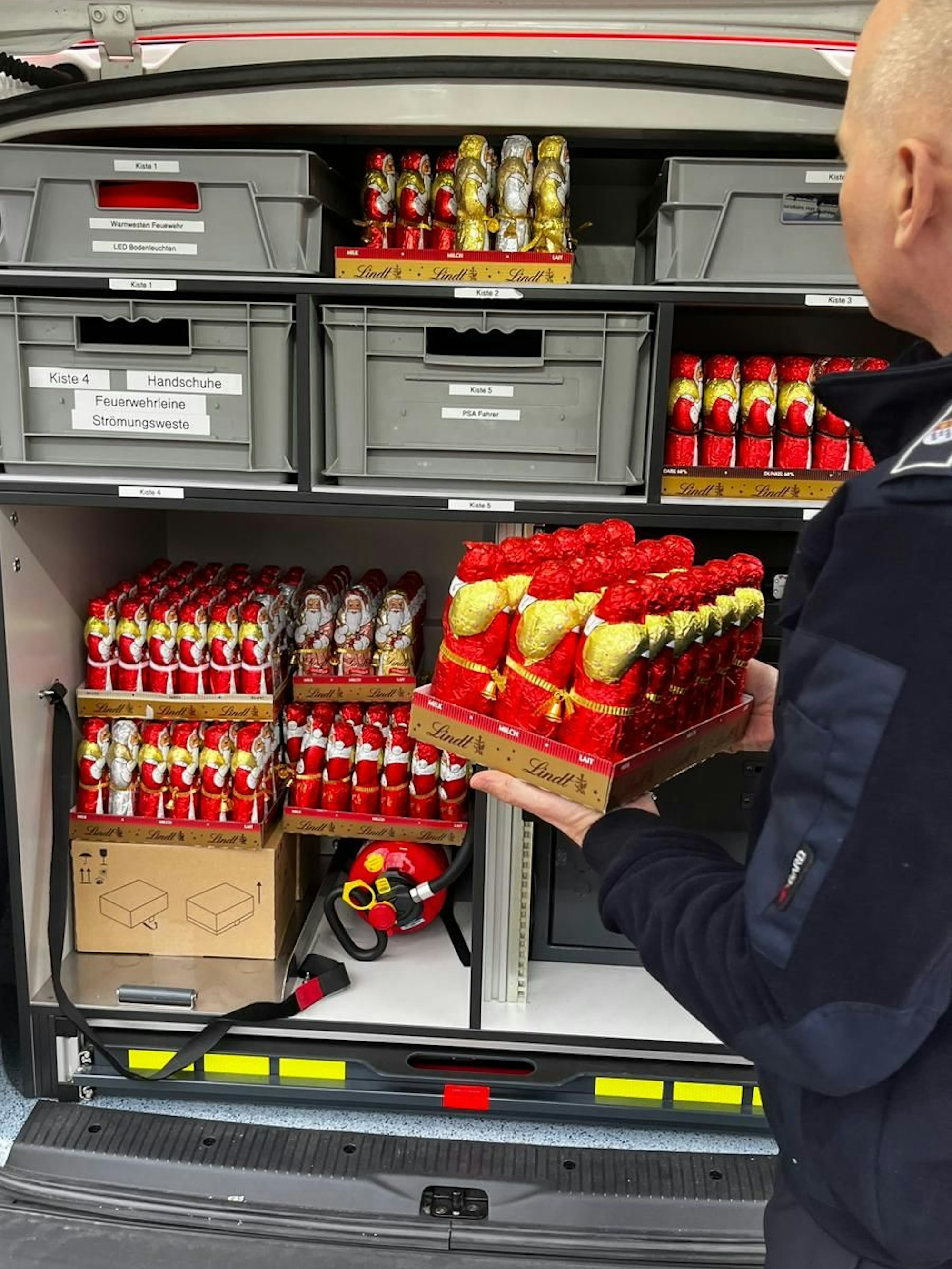 Ein Mann stellt Schoko-Nikoläuse auf Paletten in einen Rettungswagen.