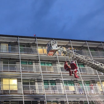 Hühenretter der Feuerwehr seilen sich in Nikolaus-Kostümen von einer Drehleiter am Krankenhaus ab.