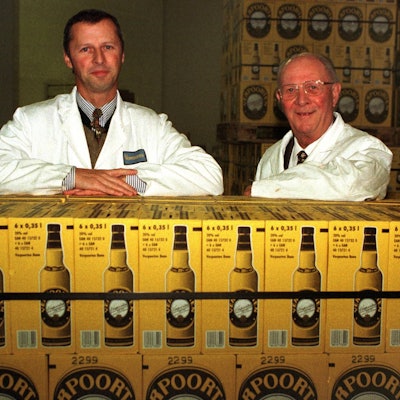 William Verpoorten (l.) und sein Sohn William lehnen auf Kisten gefüllt mit Flaschen ihres Eierlikörs. Sie lächeln beide in die Kamera.