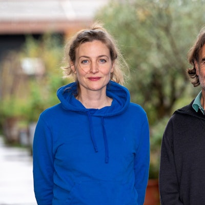 Schauspielerin Ines Marie Westernströer trägt einen blauen Hoodie, Friedhelm Friebe einen dunkelblauen Pullover über grünem Hemd. Beide lächeln.