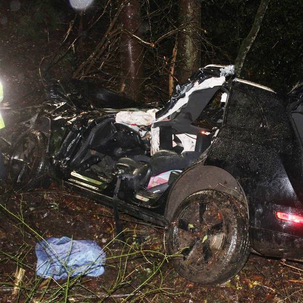 Ein schwer beschädigtes Auto, das von der Feuerwehr bereits teilweise zerlegt ist, steht in der Nacht in einer Böschung.
