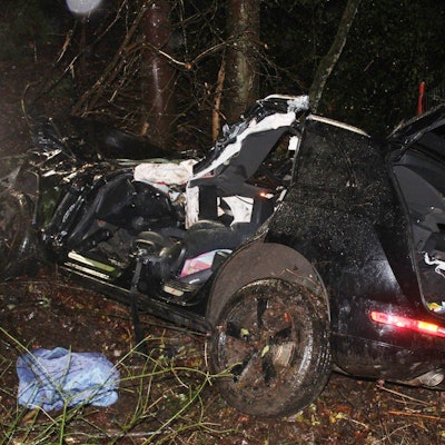 Ein schwer beschädigtes Auto, das von der Feuerwehr bereits teilweise zerlegt ist, steht in der Nacht in einer Böschung.