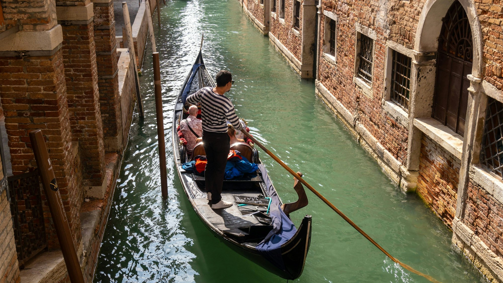 Ein kleiner Kanal in Venedig mit Touristen in einer Gondel.