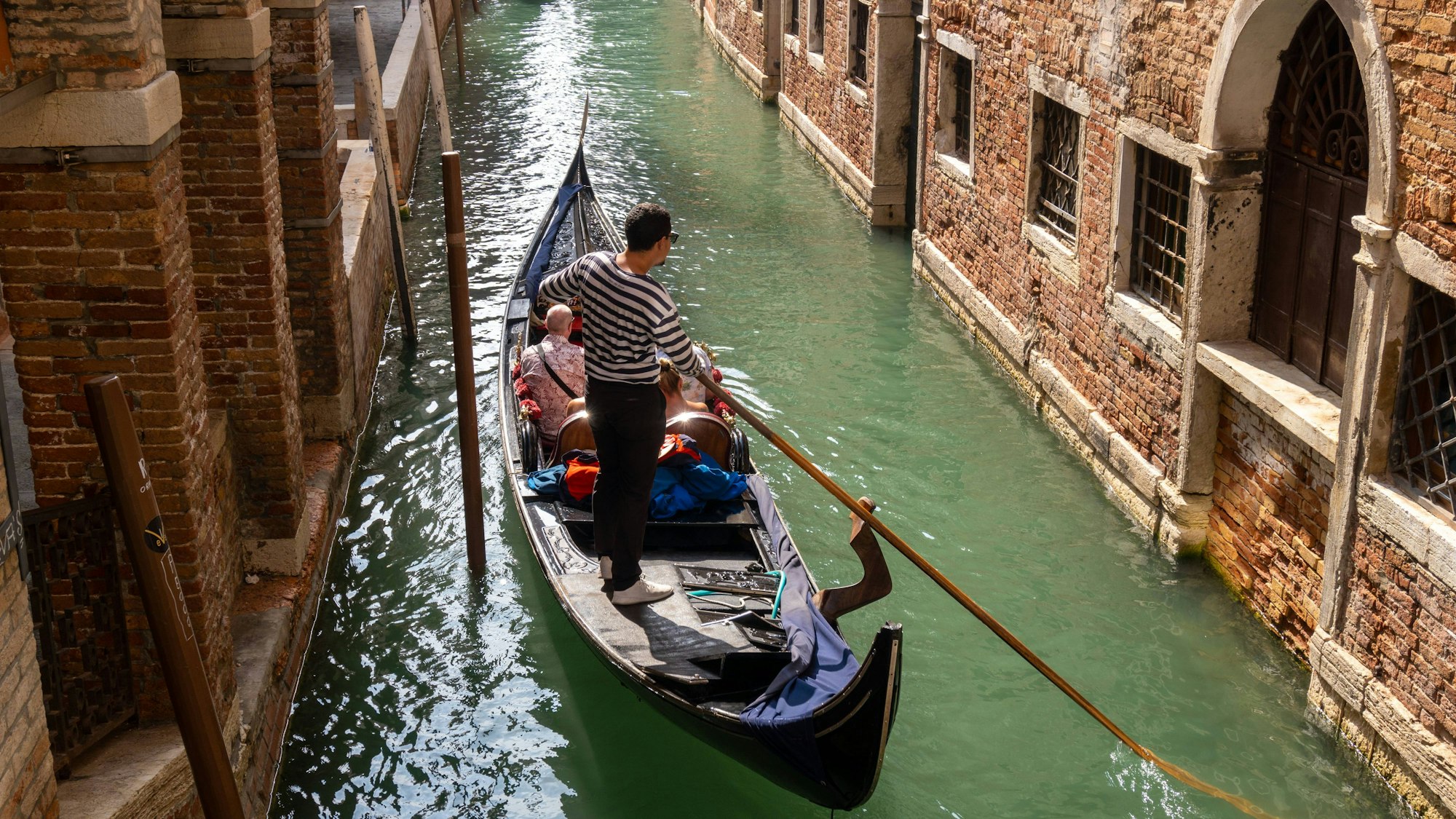 Ein kleiner Kanal in Venedig mit Touristen in einer Gondel.