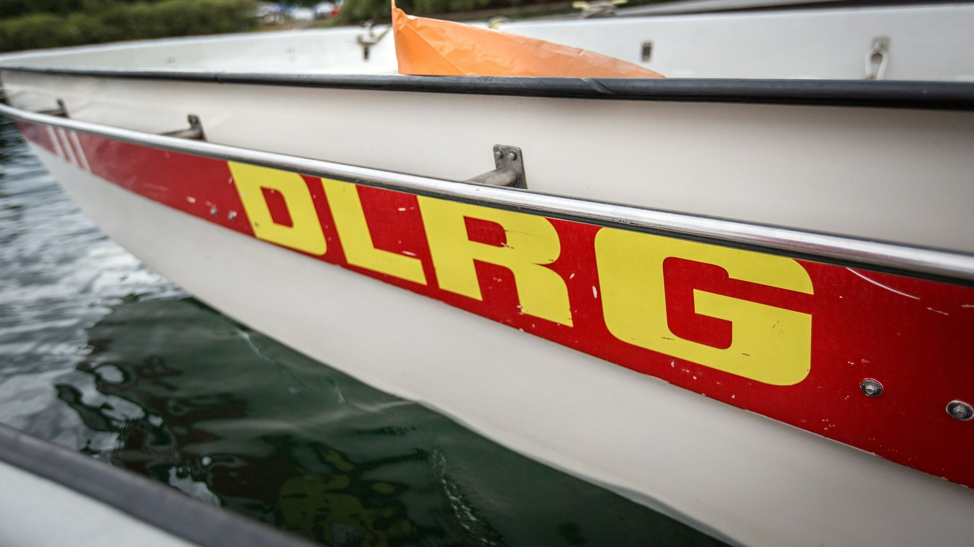Ein Boot mit der Aufschrift "DLRG Wasserrettung" der Deutsche Lebens-Rettungs-Gesellschaft (DLRG) liegt in Köln am Fühlinger See an einem Steg.