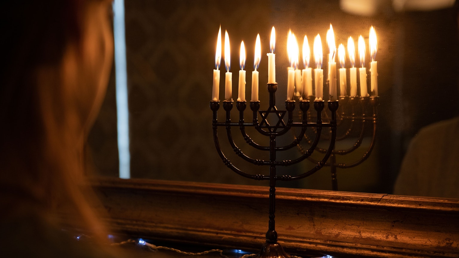 Eine Menora mit entzündeten Kerzen steht zu Chanukka im Fenster
