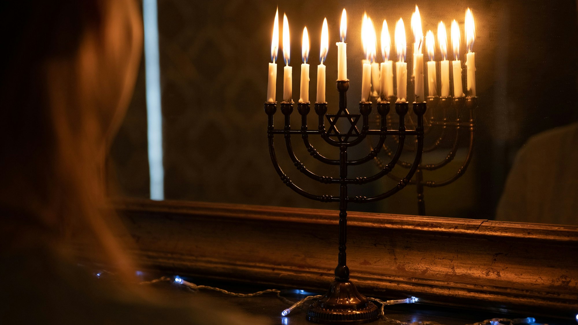 Eine Menora mit entzündeten Kerzen steht zu Chanukka im Fenster