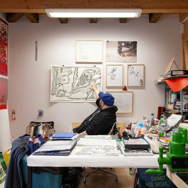 Künstler Markus Schmitz sitzt inmitten seiner Scherenschnitt-Werke im Atelier Goldstein.