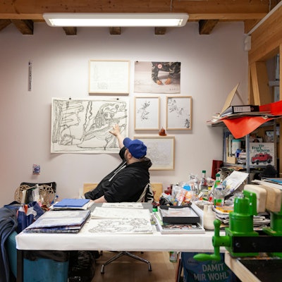 Künstler Markus Schmitz sitzt inmitten seiner Scherenschnitt-Werke im Atelier Goldstein.