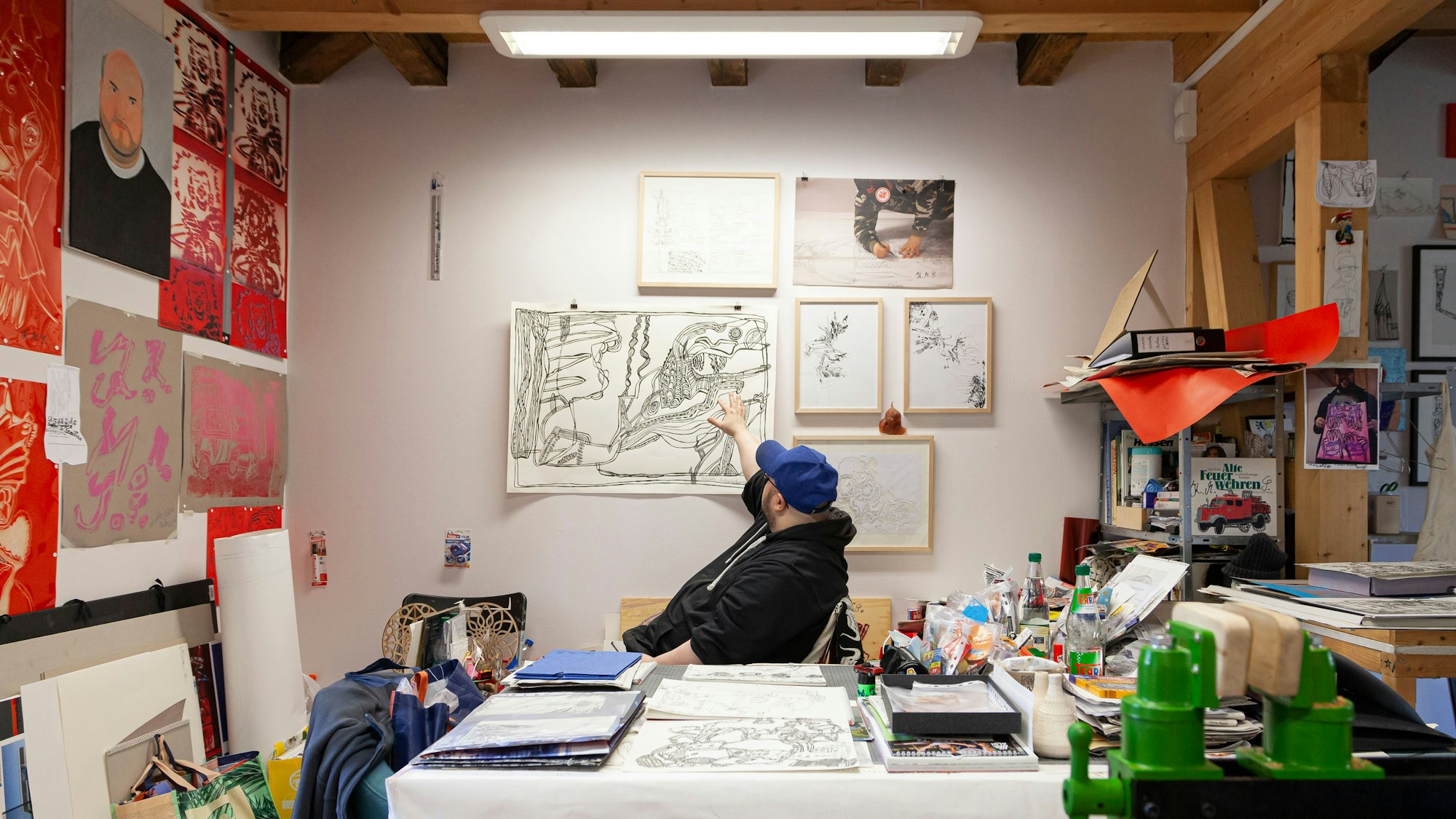 Künstler Markus Schmitz sitzt inmitten seiner Scherenschnitt-Werke im Atelier Goldstein.