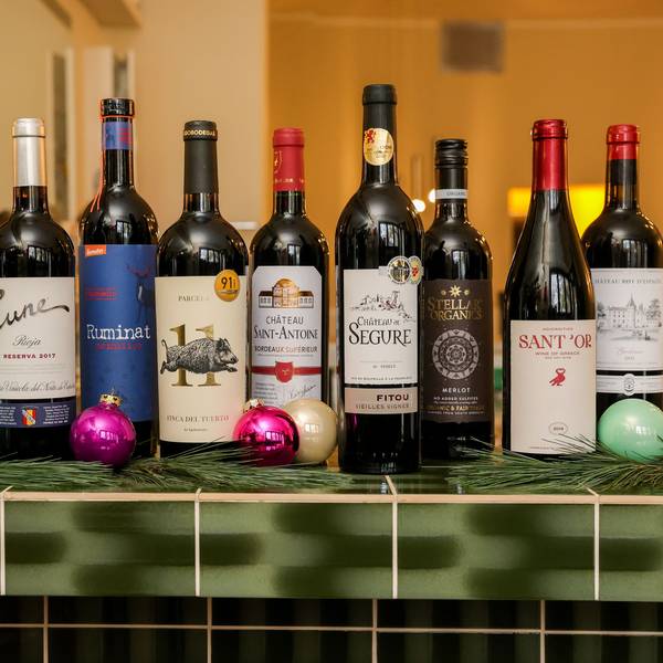 Zehn Flaschen Rotwein stehen auf einem Thekentresen, weihnachtlich geschmückt.