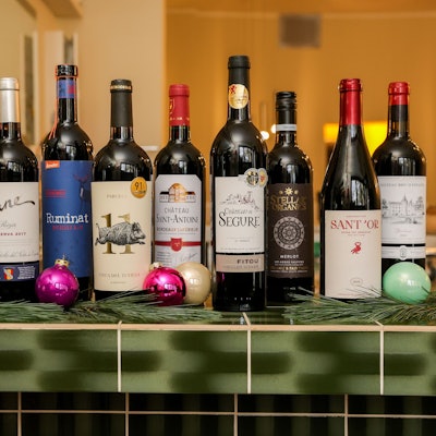 Zehn Flaschen Rotwein stehen auf einem Thekentresen, weihnachtlich geschmückt.